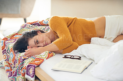 Buy stock photo Cropped portrait of a young woman lying beside reading material on her bed