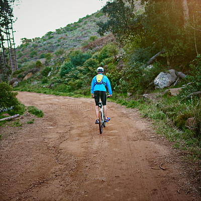 Buy stock photo Rearview shot of a male cyclist riding along a mountain bike trail