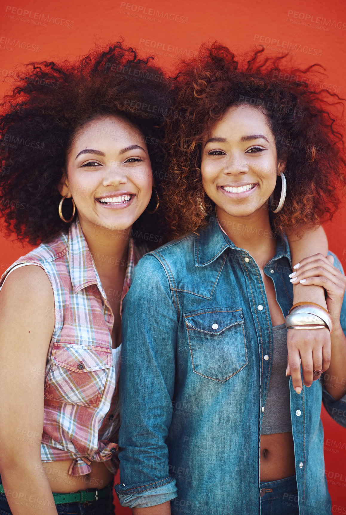 Buy stock photo Shot of two young friends posing against a red background