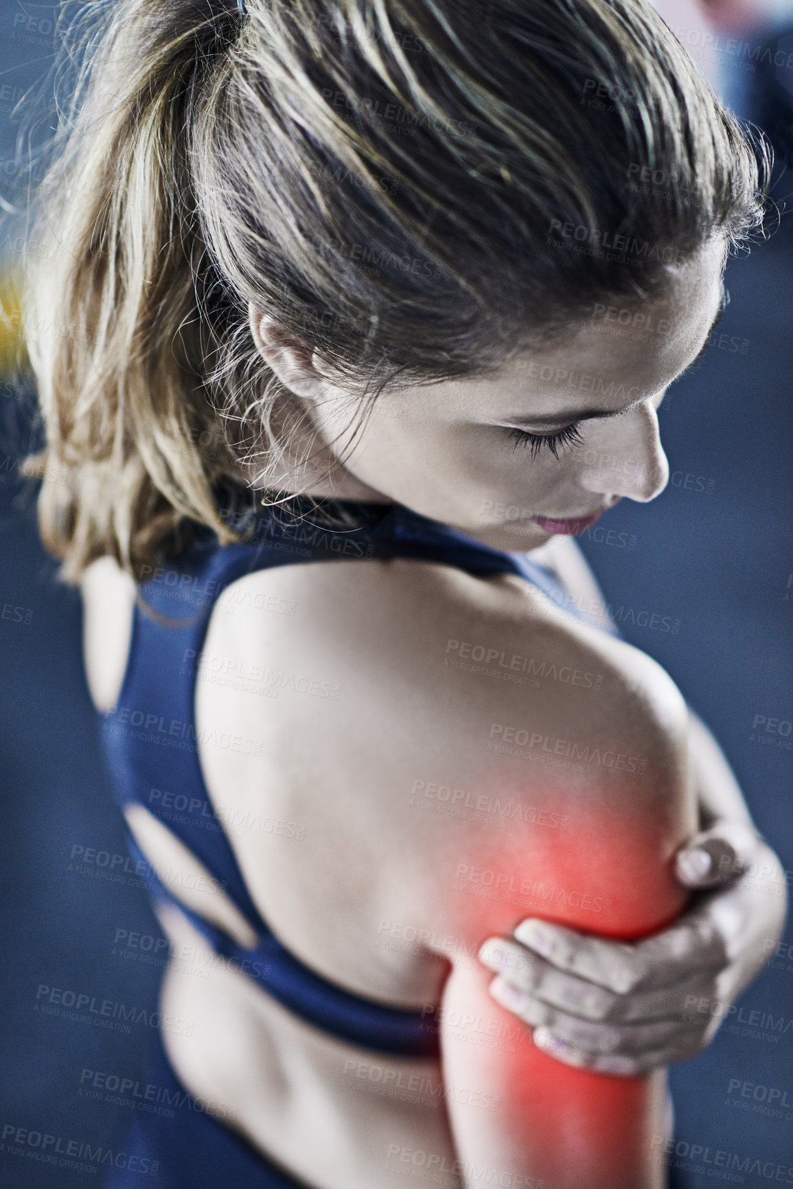 Buy stock photo Shot of a young woman holding her injured shoulder that's highlighted in red