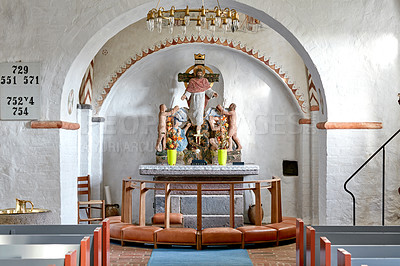 Buy stock photo Interior of a historical church with rows of benches, a nave or alter with kneeler cushions and Jesus hanging on a cross. 12th century old public Danish National Church in Faarup, Denmark