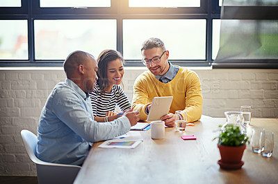 Buy stock photo Shot of a group of designers working together on a digital tablet