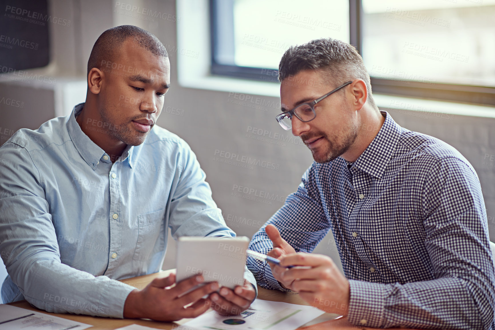 Buy stock photo Shot of two designers working on a digital tablet in an office