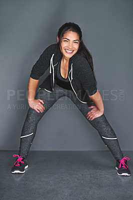Buy stock photo Shot of a fit young woman stretching her legs against a gray background