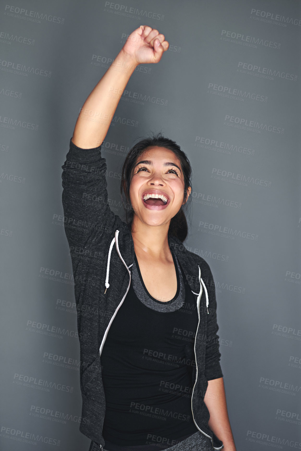 Buy stock photo Shot of an excited young woman in sports clothing punching the air