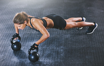 Buy stock photo Shot of a young woman working out with kettlebells