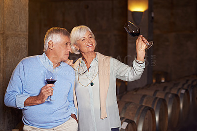 Buy stock photo Cropped shot of an affectionate senior couple wine tasting in a cellar