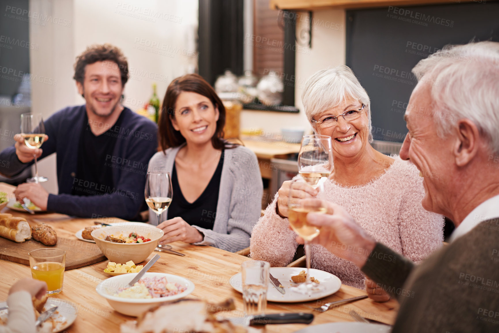 Buy stock photo Smile, cheers and family at dinner in dining room for party, celebration or event at modern home. Happy, bonding and group of people enjoying meal, supper or lunch together with wine at house.