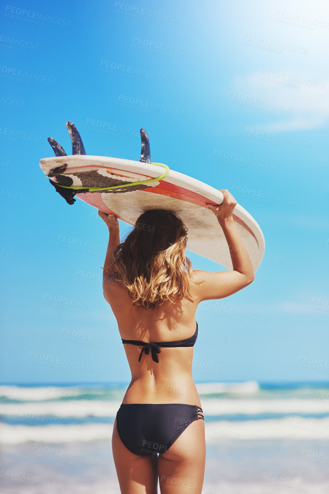 Buy stock photo Rearview shot of a young surfer holding her surfboard on her head at the beach