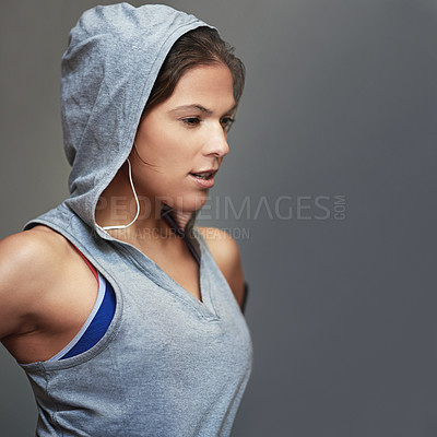 Buy stock photo Shot of a sporty young woman wearing a hoodie posing against a gray background