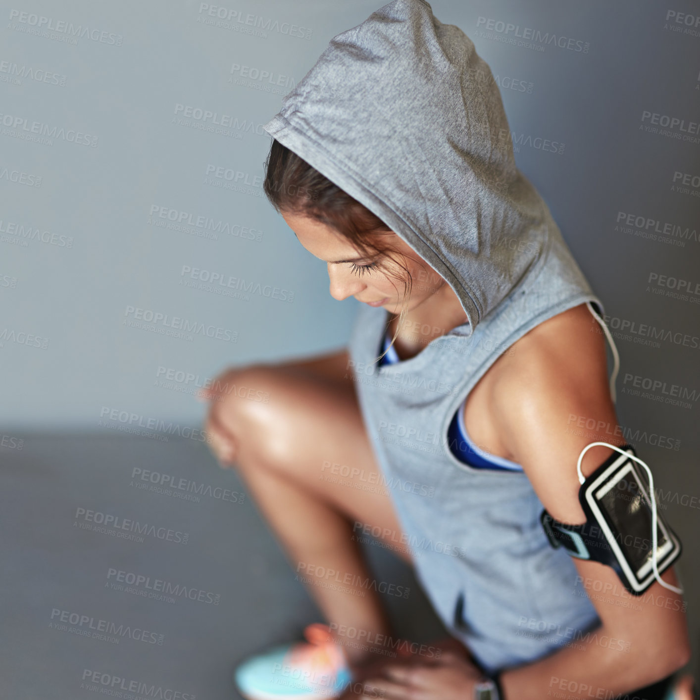 Buy stock photo Woman, thinking and athlete break in studio with cellphone pouch, earphones or grey background. Female person, contemplating and workout resting or music playlist for podcast app, thoughts or relax