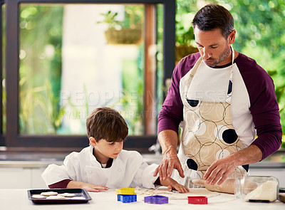 Buy stock photo Shot of a father and son baking biscuits in the kitchen