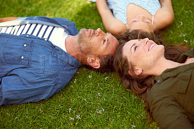 Buy stock photo High angle shot of a young family lying on the grass outside