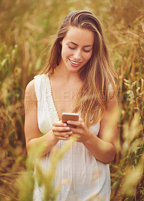 Buy stock photo Countryside, cellphone and woman in spring, outdoor and texting in nature, fun and smile for message. Grass, communication and fresh air in meadow, peace and typing with mobile, person and online