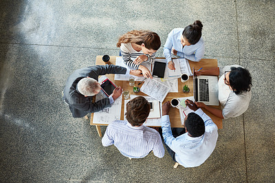 Buy stock photo High angle shot of a group of coworkers sitting around a table in the boardroom