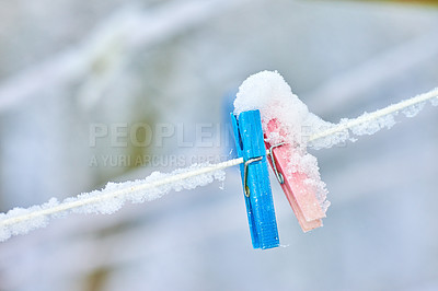 Buy stock photo Multi Colored clothing pins on a rope in hoarfrost hang on a rope in the winter outside in the snow. Blue and red pegs with ice over them attached to a washing line during winter on a cold day 
