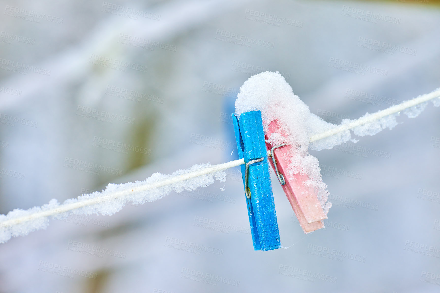 Buy stock photo Multi Colored clothing pins on a rope in hoarfrost hang on a rope in the winter outside in the snow. Blue and red pegs with ice over them attached to a washing line during winter on a cold day 
