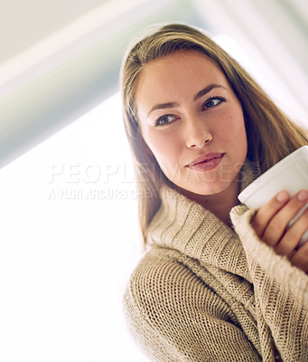 Buy stock photo Shot of a thoughtful young woman enjoying a warm beverage at home