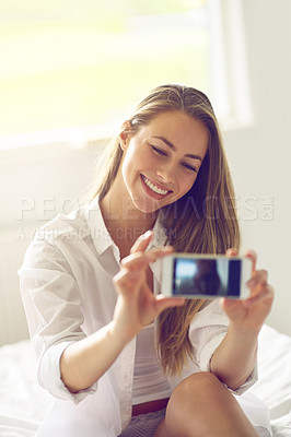 Buy stock photo Shot of a young woman taking a morning selfie in her bedroom