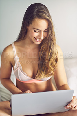 Buy stock photo Shot of a young woman using a laptop in her underwear during the morning