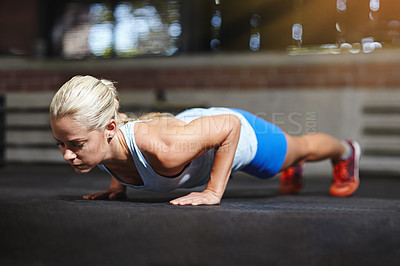 Buy stock photo Shot of a young woman doing pushups in a gym