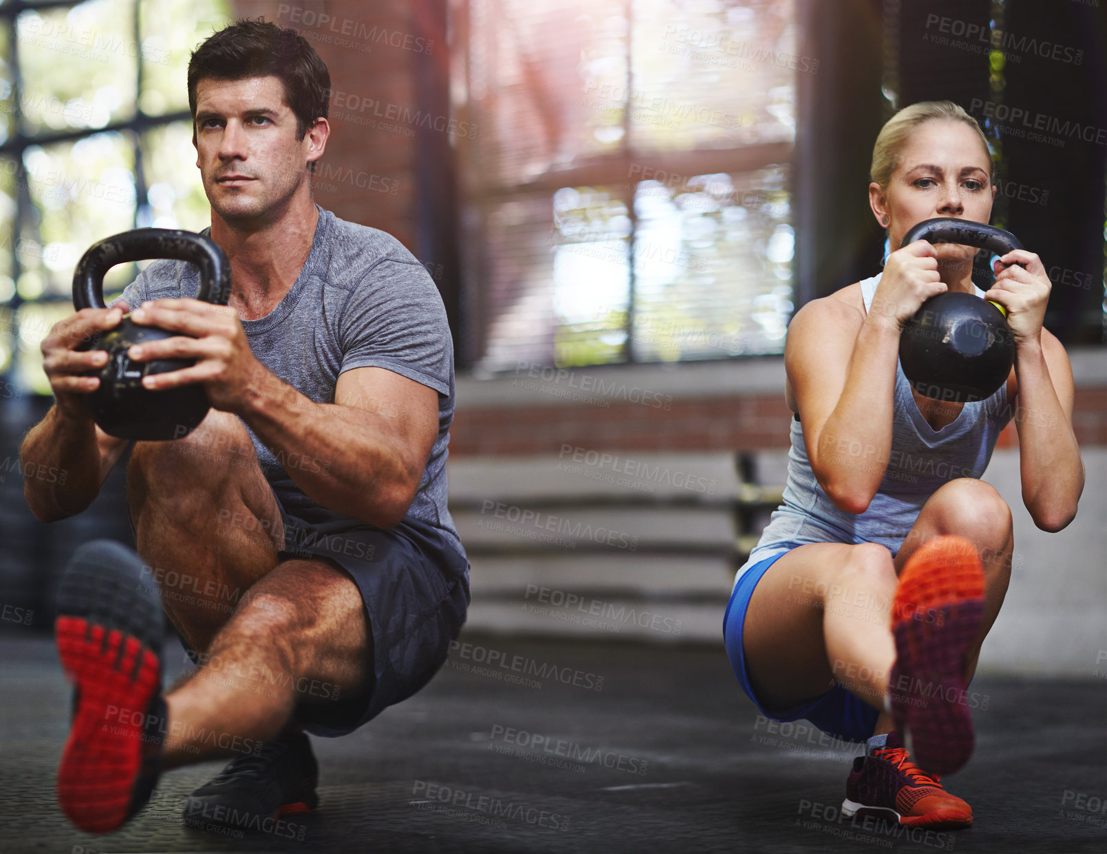 Buy stock photo Shot of two people working out with kettlebells in a gym