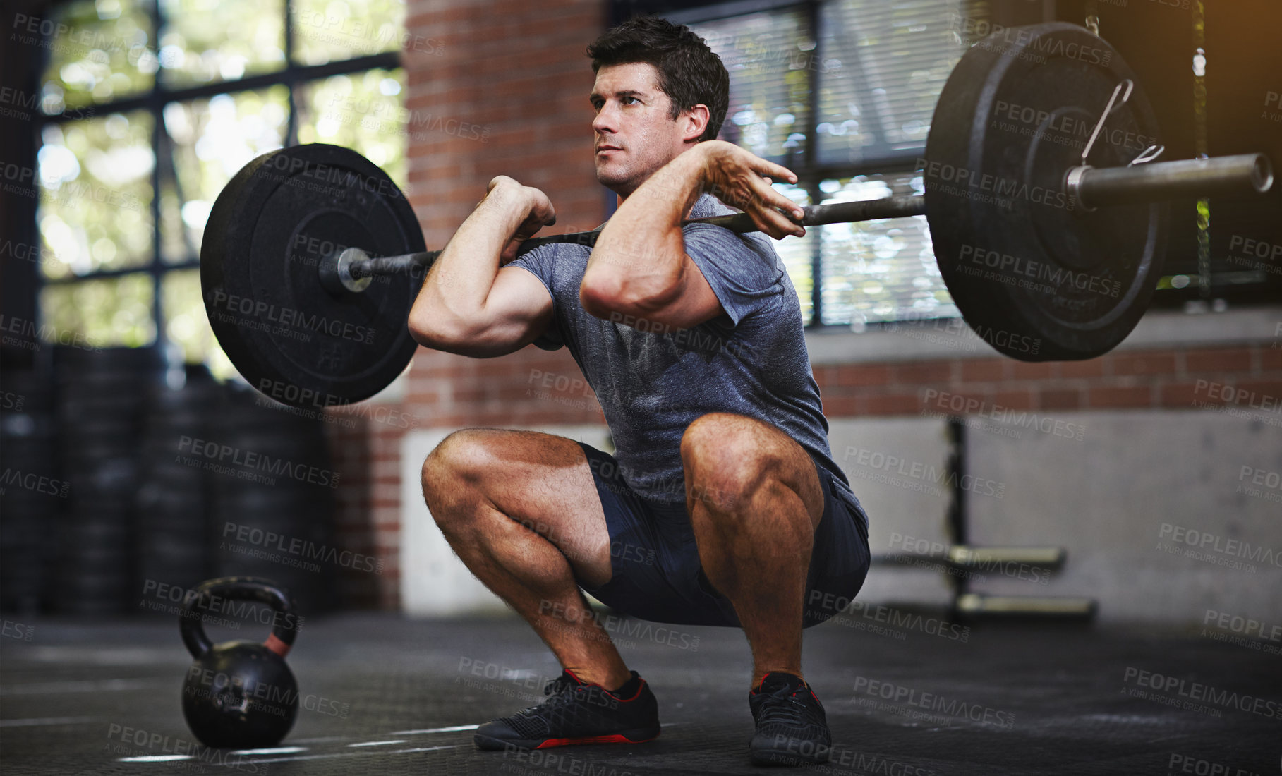 Buy stock photo Shot of a young man lifting weights in a gym