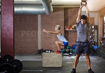 Buy stock photo Shot of two people working out with kettlebells in a gym