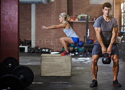 Buy stock photo Shot of two people working out with kettlebells in a gym