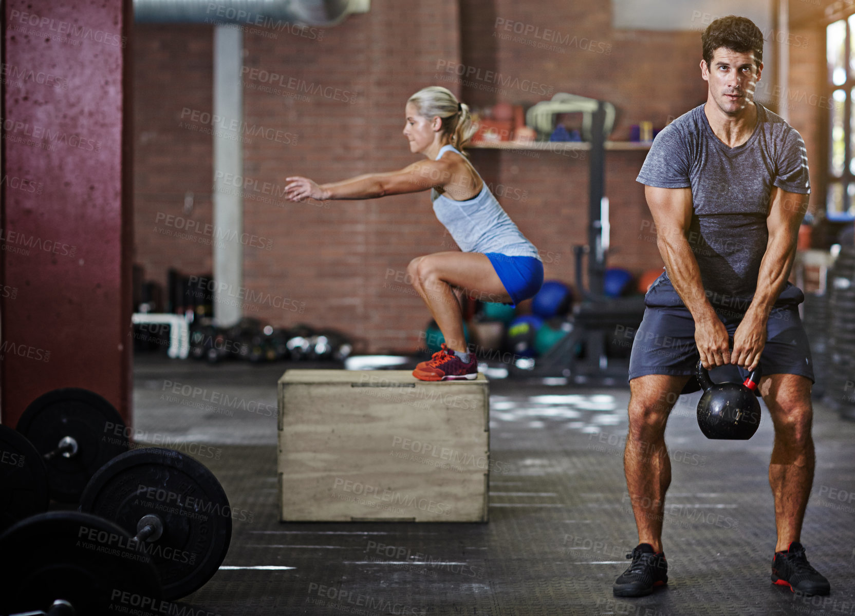 Buy stock photo Shot of two people working out with kettlebells in a gym