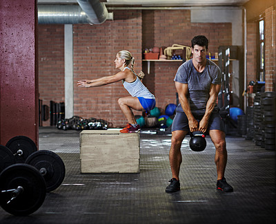 Buy stock photo Shot of two people working out with kettlebells in a gym