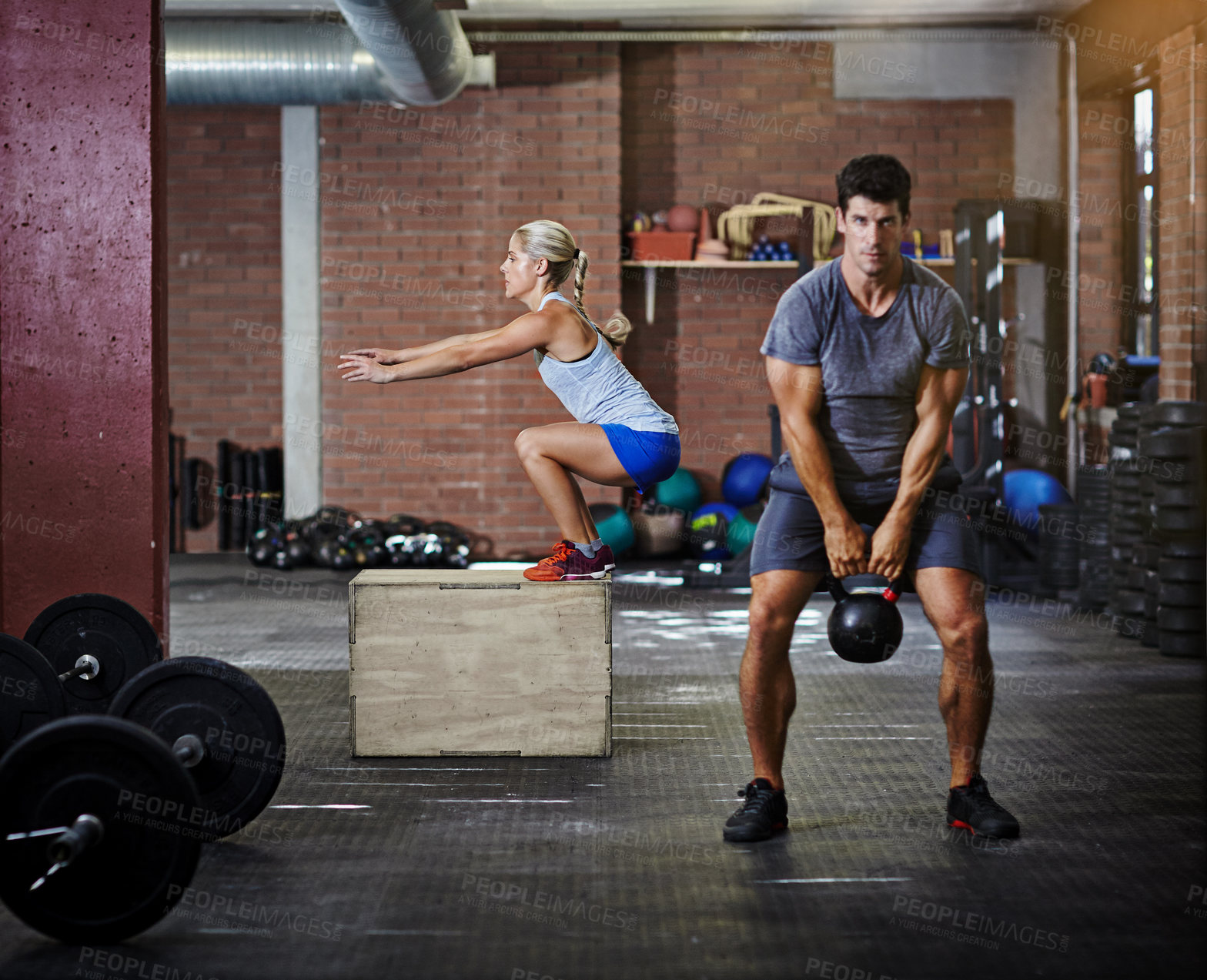 Buy stock photo Shot of two people working out with kettlebells in a gym