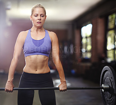 Buy stock photo Shot of a young woman lifting weights in a gym