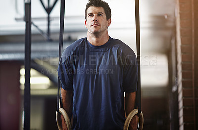 Buy stock photo Shot of a young man working out with gymnastics rings in a gym