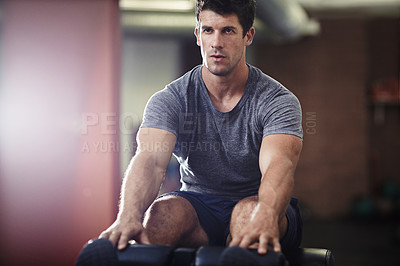 Buy stock photo Shot of a young man doing sit ups in a gym