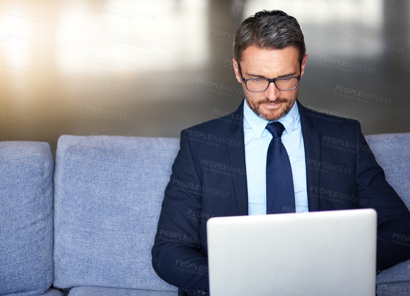 Buy stock photo Shot of a businessman using a laptop on the sofa