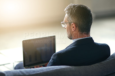 Buy stock photo Rearview shot of a businessman using a laptop in the office