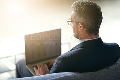 Buy stock photo Rearview shot of a businessman using a laptop in the office