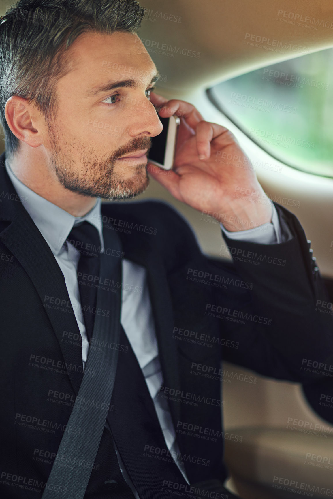 Buy stock photo Cropped shot of a businessman using his cellphone while sitting in the backseat of a car