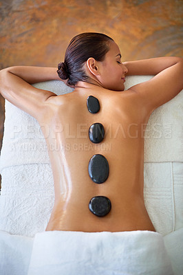 Buy stock photo Shot of a young woman enjoying a hot stone massage at a spa