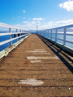 Buy stock photo A wood pier leading into the ocean with copy space. An old empty platform or dock terrace on a lake with blue water. Wooden jetty, old bridge or a wharf near a lakehouse getaway retreat during summer