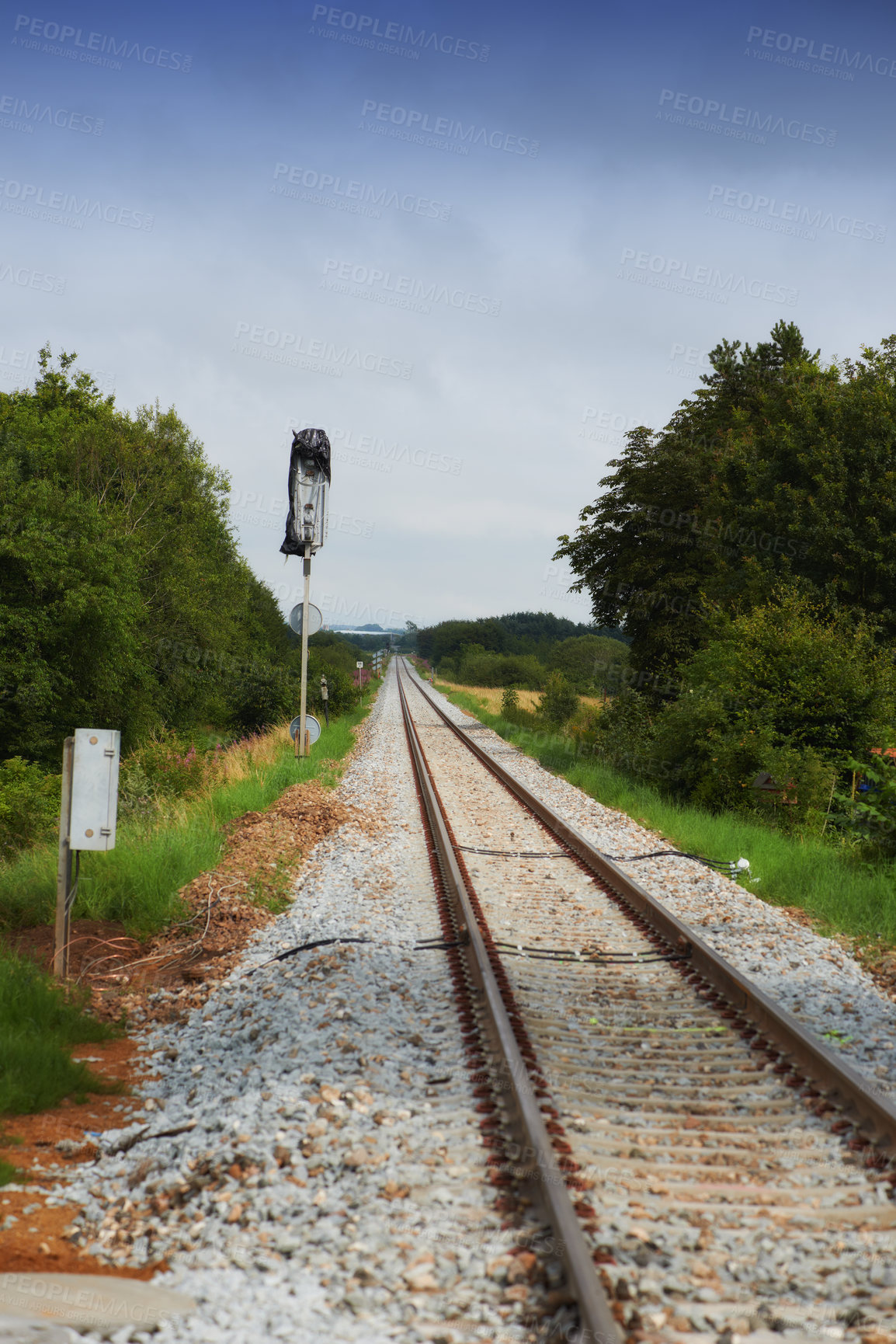 Buy stock photo Long empty train tracks running through a forest. Old train rails on stony ground between green lush trees, grass and plants during the day. Railroad surrounded by nature near countryside