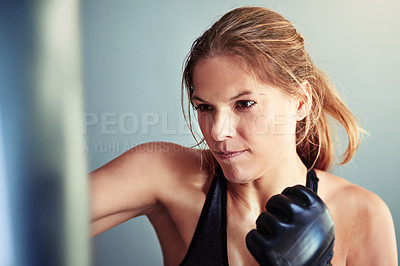 Buy stock photo Shot of a female boxer training with a punching bag