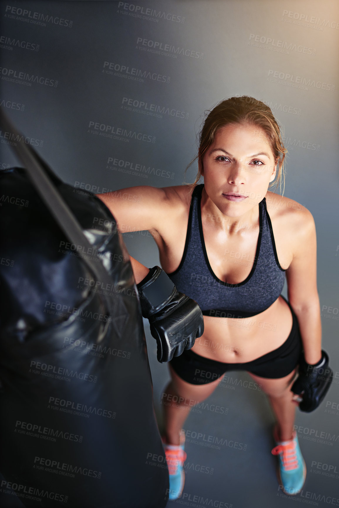 Buy stock photo Portrait of a female boxer leaning against a punching bag