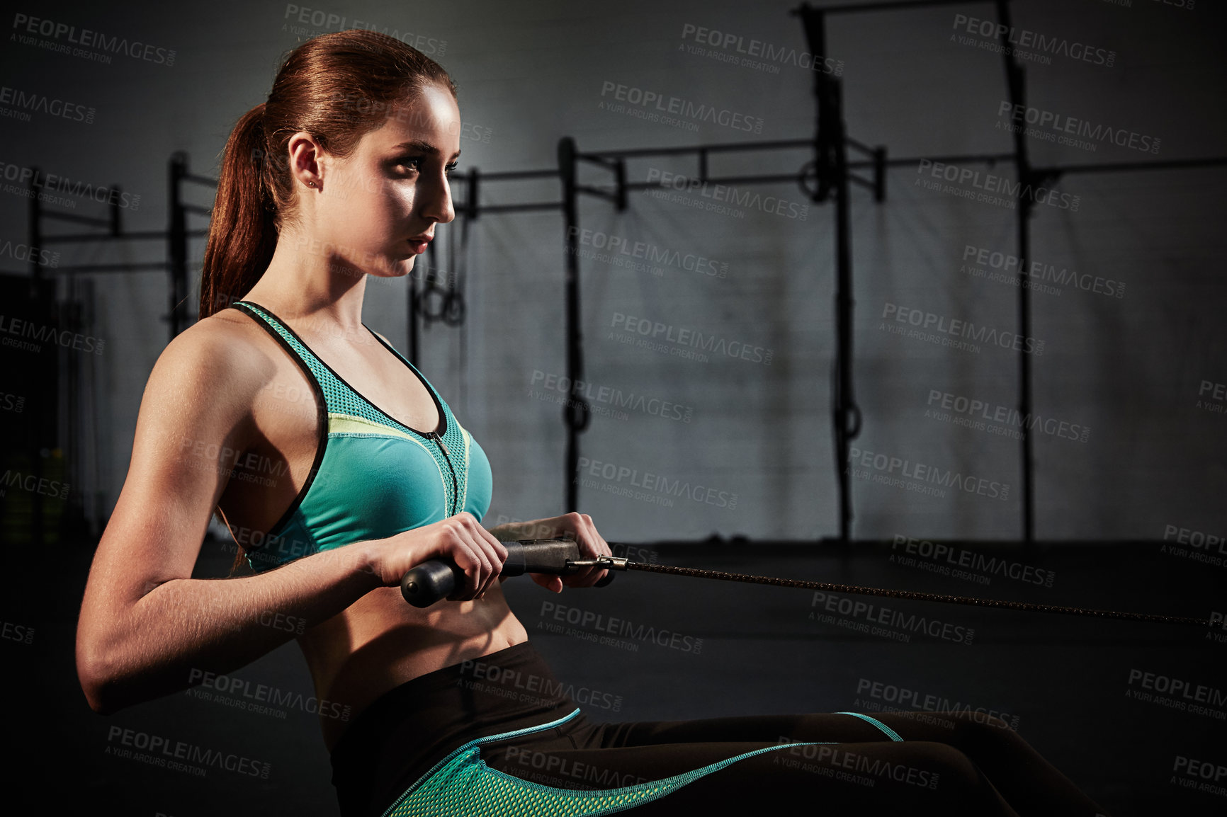 Buy stock photo Shot of a young woman working out on a rowing machine