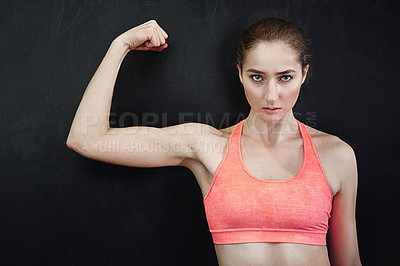 Buy stock photo Shot of a young woman flexing her muscles