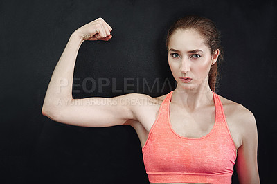 Buy stock photo Shot of a young woman flexing her muscles