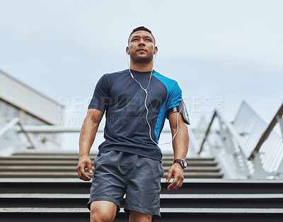Buy stock photo Low angle shot of a male runner standing on steps in the city