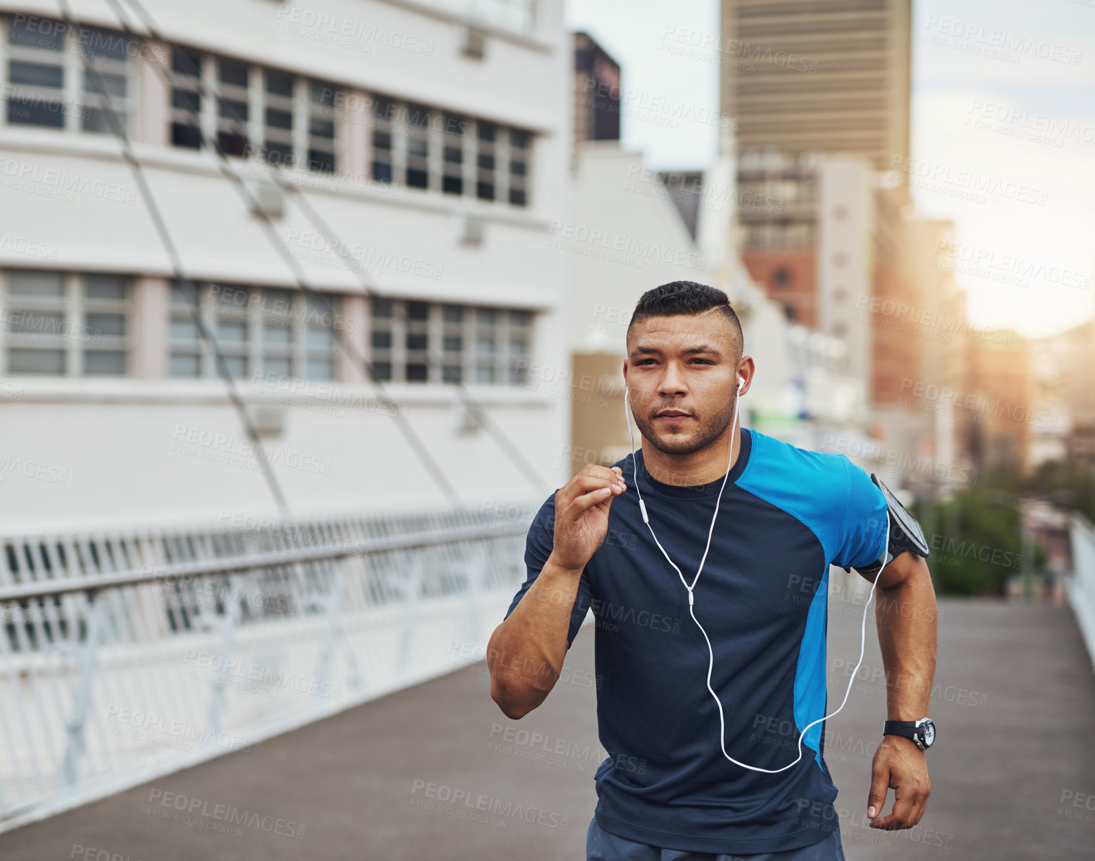 Buy stock photo Fitness, running and man on bridge in city with health, wellness or earphones for streaming. Urban workout, body care and runner listening to music, podcast or training in street for morning exercise