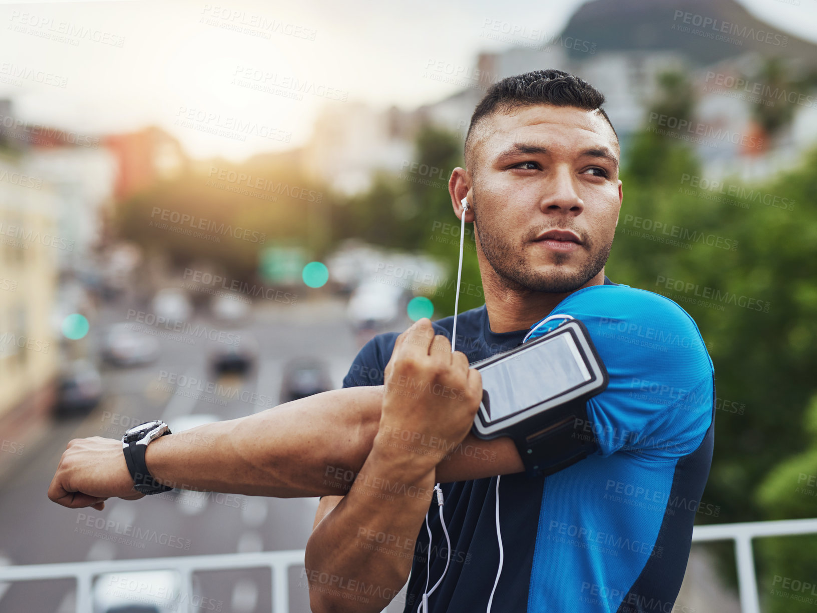 Buy stock photo Shot of a young man stretching before a run in the city